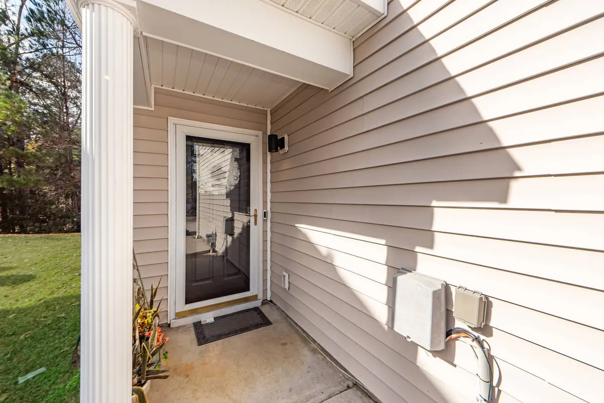 A close-up of the home's front entryway, with a decorative column, welcome mat, and well-tended landscaping. The image suggests warmth, hospitality, and the significance of returning home to a soothing environment.