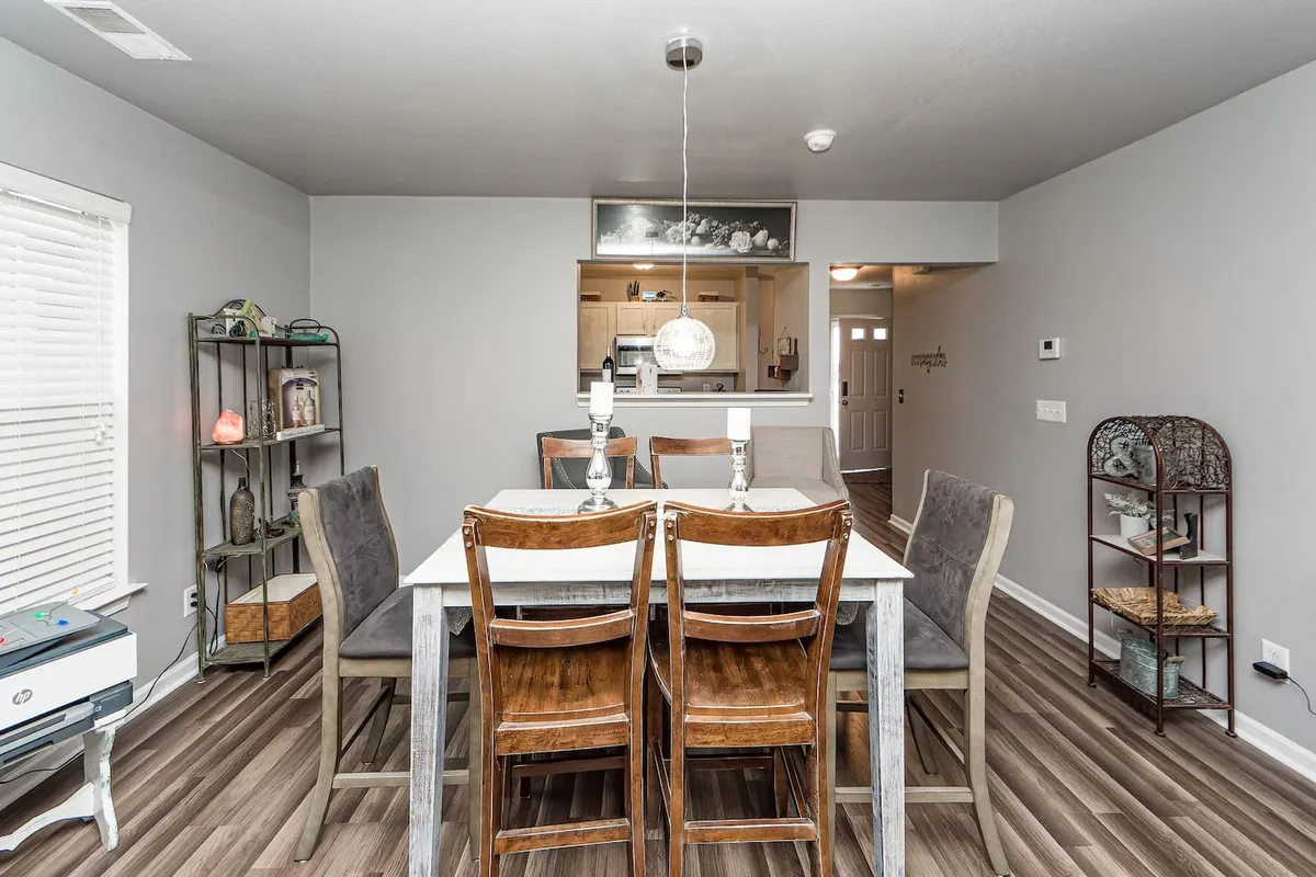 The image showcases a well-appointed dining area adjacent to the kitchen, featuring a central dining table, a shelf unit, and stylish lighting. The inviting space is perfect for gathering with family or friends before or after enjoying movie nights.