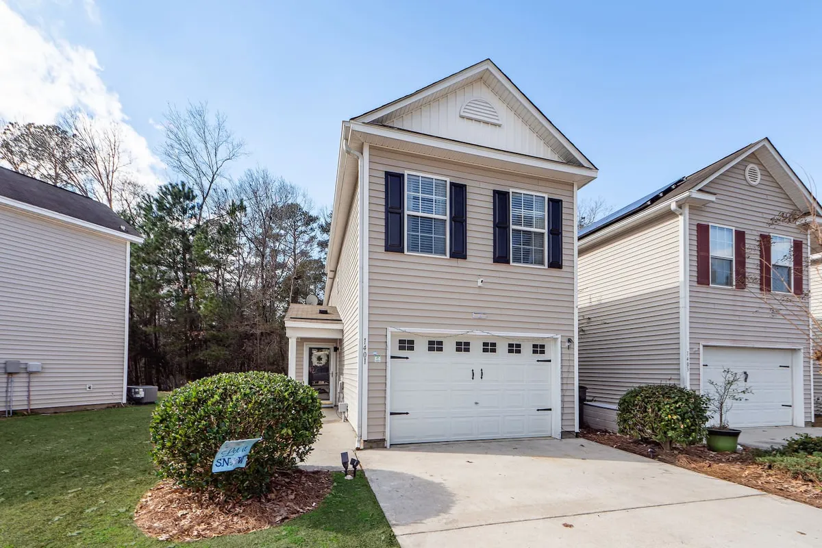 This exterior image captures the front door and garage of the home, framed by a neatly landscaped yard. The welcoming appearance of the front entryway and the surrounding greenery create a sense of safety and comfort.