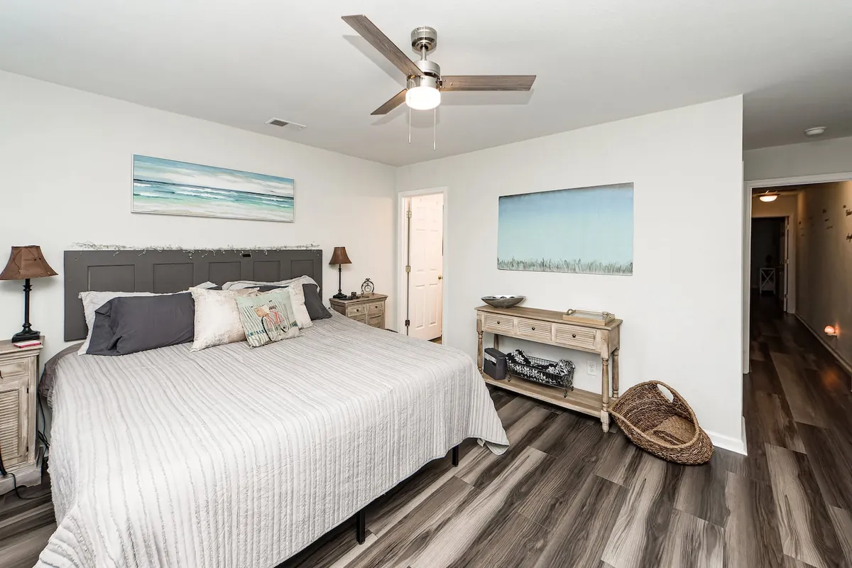 A peaceful bedroom centered around a bed with textured bedding and plush pillows, complemented by soft lighting from matching nightstands and tranquil artwork on the walls. The overall ambiance is restful, with soothing tones and minimal distractions.